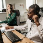 2 customer service members of staff answering mystery shopping calls in an office.